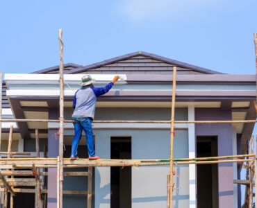 Asian,Construction,Worker,On,Wooden,Scaffolding,Is,Painting,Roof,Structure